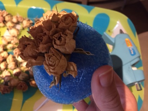 Using your glue gun, start attaching the roses to the base.